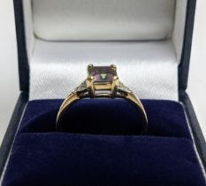 A 9CT GOLD MYSTIC TOPAZ DRESS RING, the emerald cut stone claw set with a diamond encrusted