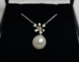 A 9CT WHITE GOLD CULTURED PEARL AND DIAMOND SNOWFLAKE PENDANT NECKLACE, fitted on a fine link chain,