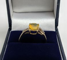 A 9CT GOLD YELLOW OPAL RING WITH DIAMOND-SET TWIST SHOULDERS, the oval cut opal claw set, ring