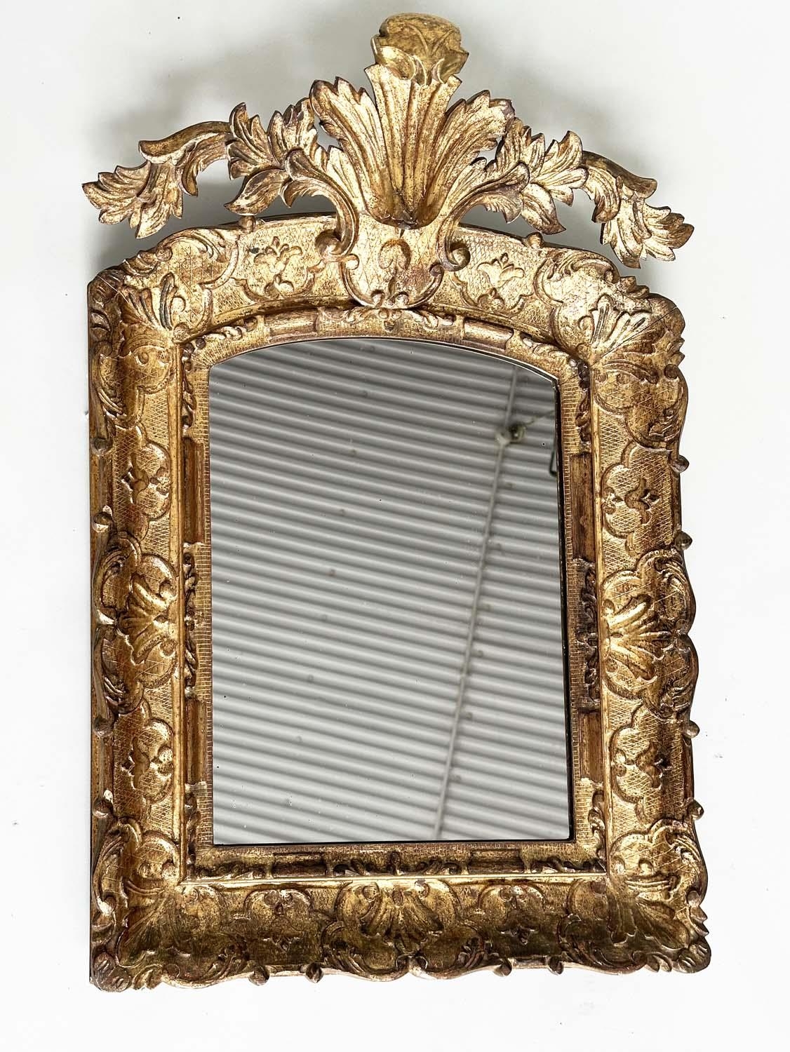 WALL MIRROR, early 19th century Italian carved giltwood grotto style arched with foliate crest, 76cm