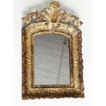 WALL MIRROR, early 19th century Italian carved giltwood grotto style arched with foliate crest, 76cm