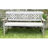 GARDEN BENCH, well weathered silvery teak of slatted construction with lattice panelled back,