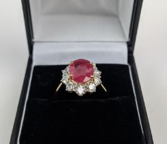 AN 18CT GOLD RUBY AND DIAMOND CLUSTER RING, the mixed cut ruby of 4.11 carats, surrounded by ten