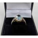 A 14CT GOLD AQUAMARINE AND DIAMOND SET DRESS RING, the mixed cut aquamarine stone surrounded by halo