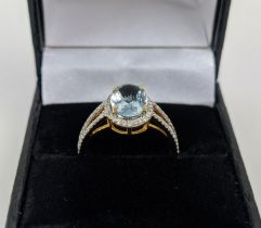 A 14CT GOLD AQUAMARINE AND DIAMOND SET DRESS RING, the mixed cut aquamarine stone surrounded by halo