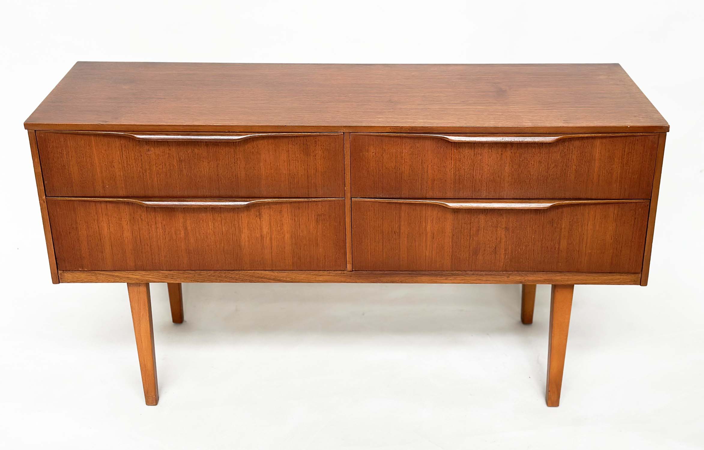 AUSTIN SUITE LOW CHEST, 1970s teak with four drawers, 128cm W x 70cm H x 41cm D.