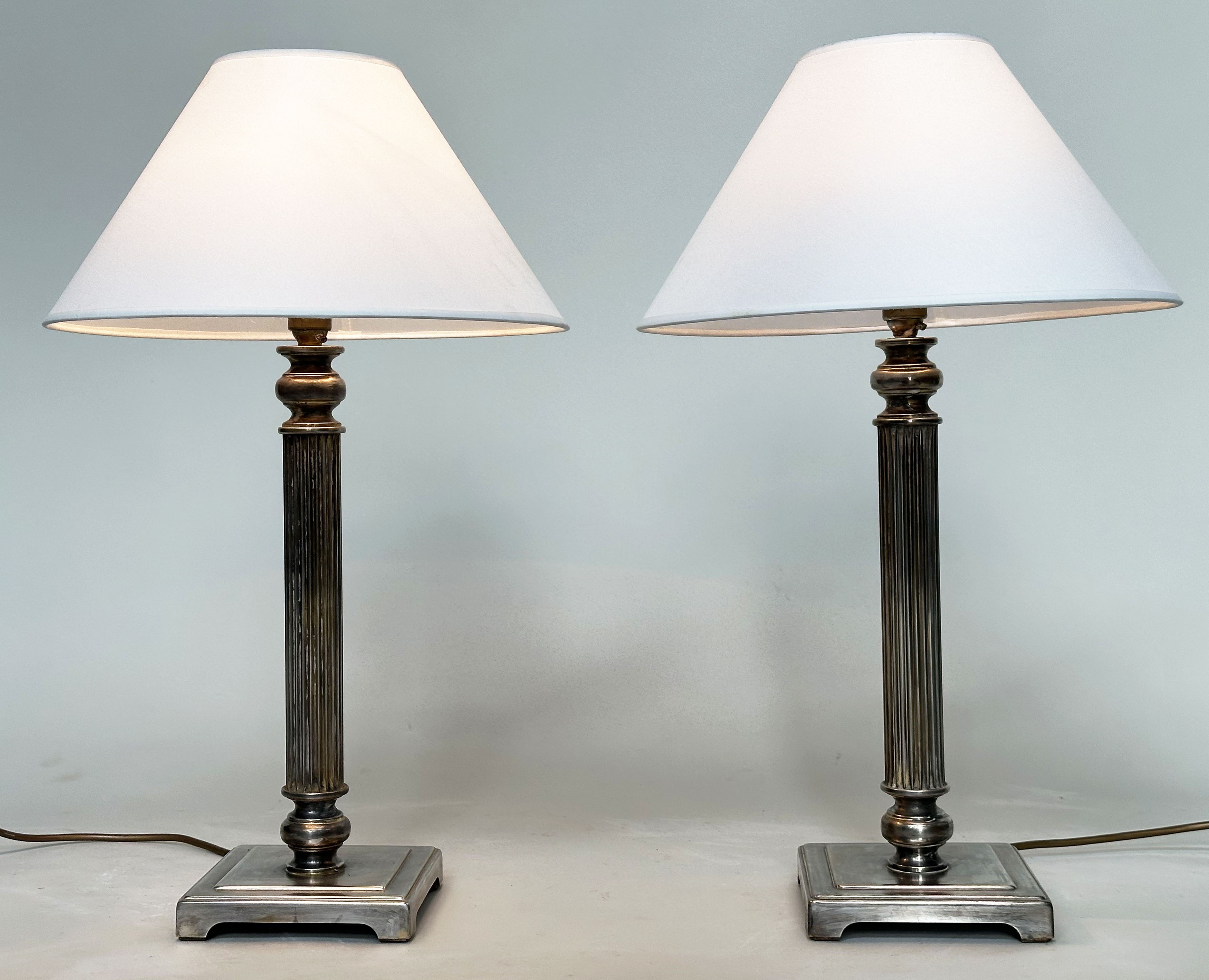 TABLE LAMPS, a pair, silvered metal each with reeded column, and square bases (with shades), 66cm H.
