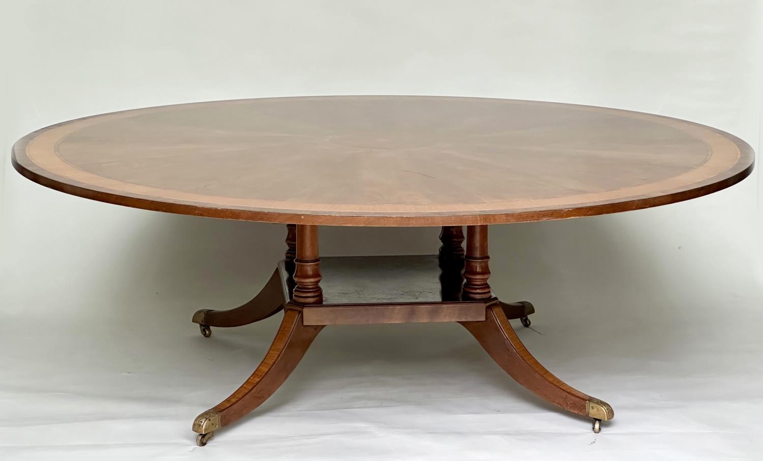 DINING TABLE, circular Regency style radially veneered mahogany and satinwood crossbanded with