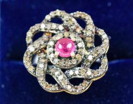 A RUBY AND DIAMOND DRESS RING, white metal shank, the flower head setting with a central ruby