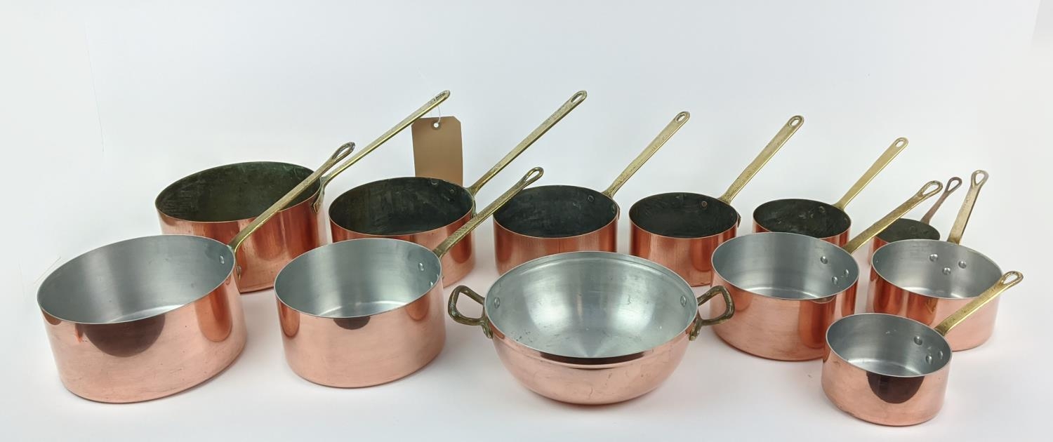 BATTERIE DE CUISINE, a graduated set of twelve, copper pans, with brass handles. (12)