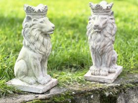 GARDEN LIONS, a pair, weathered composite stone each seated and crowned, 35cm H. (2)