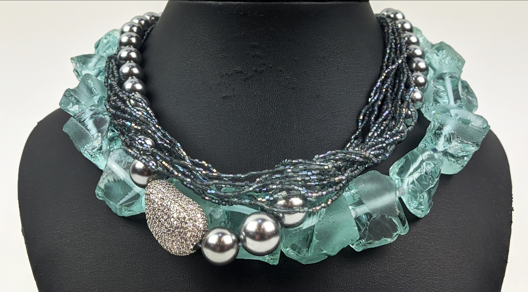 AN AQUAMARINE COLOURED ROUGH STONE NECKLACE, with a paste diamond clasp, 46cm long, together with