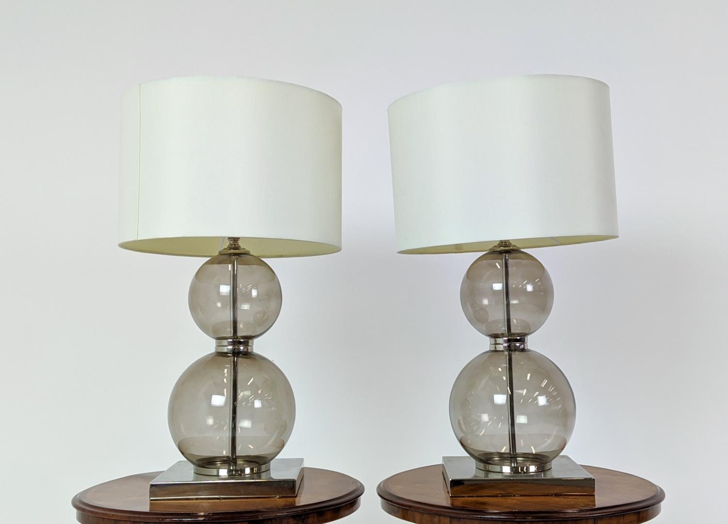 TABLE LAMPS, a pair, glass ball stems on square polished metal bases, 61cm H x 35cm W in shades. (2)