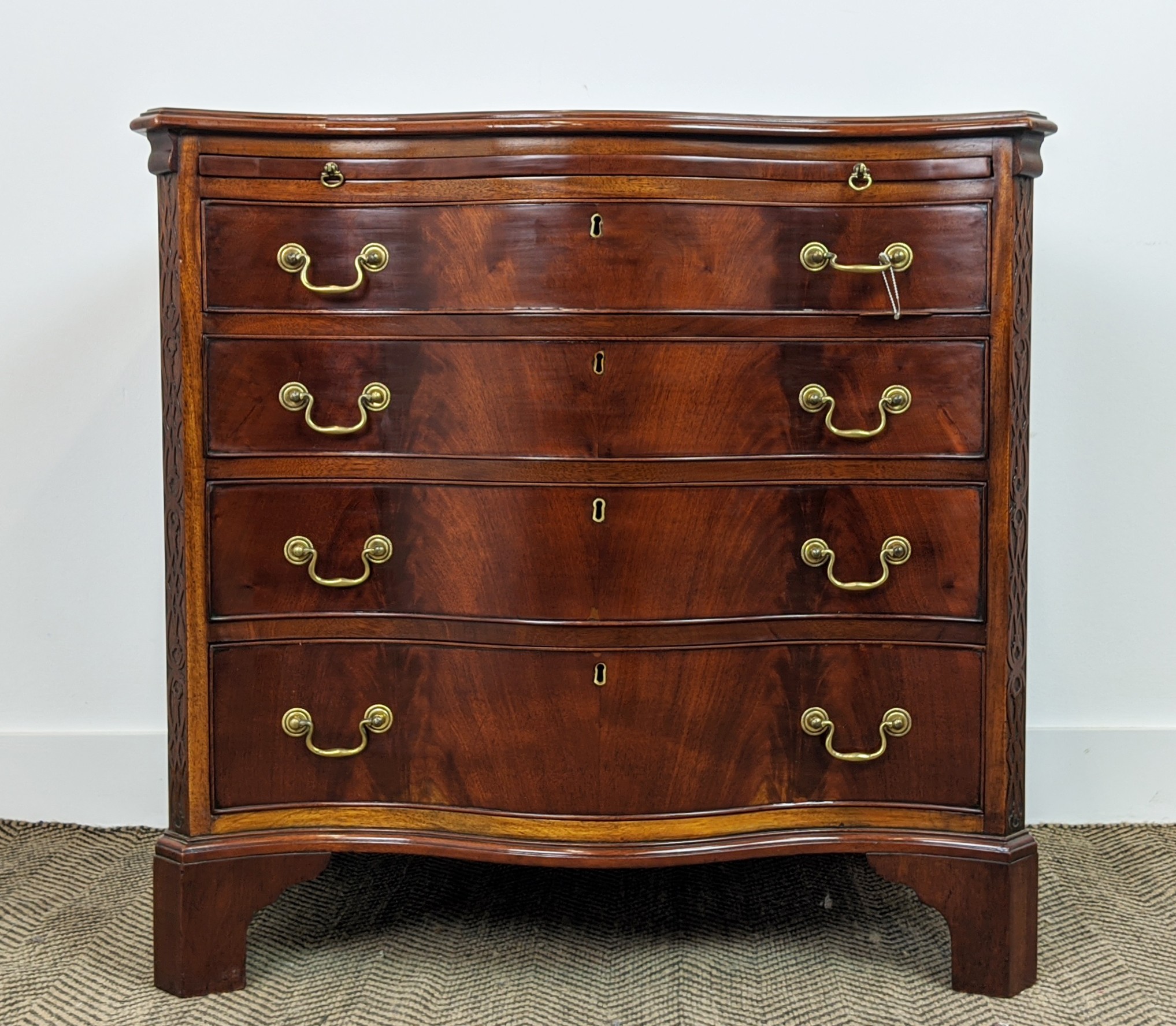 SERPENTINE CHEST, George III style mahogany with brushing slide above four drawers, 78cm H x 81cm