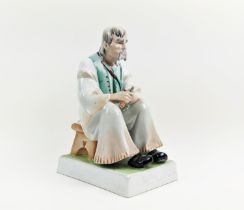 A ZSOLNAY FIGURE OF A MAN WITH A KNIFE, seated, made in Hungary, hand painted, 33cm high