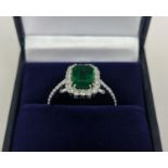 AN 18CT WHITE GOLD EMERALD AND DIAMOND SET DRESS RING, the central step-cut emerald of approximately