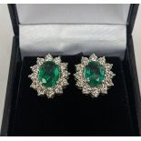 A PAIR OF 18CT WHITE GOLD EMERALD AND DIAMOND CLUSTER STUD EARRINGS, the oval mixed cut emerald