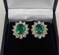 A PAIR OF 18CT WHITE GOLD EMERALD AND DIAMOND CLUSTER STUD EARRINGS, the oval mixed cut emerald