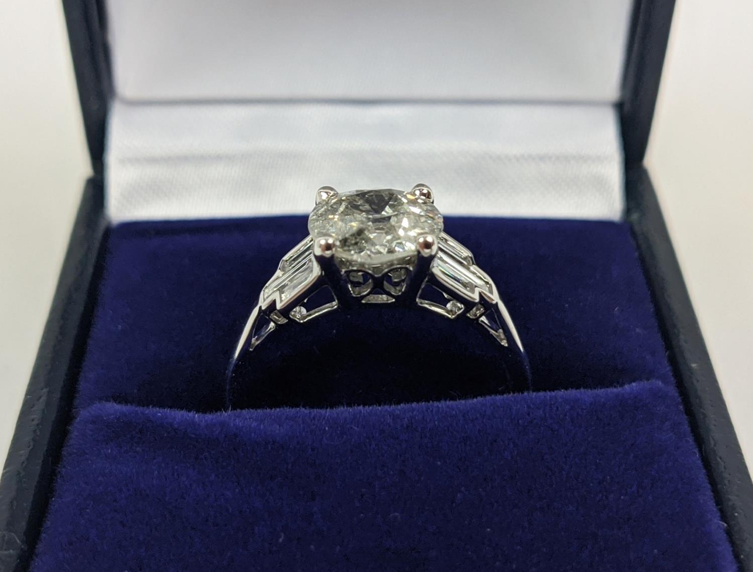 AN 18CT WHITE GOLD DIAMOND SOLITAIRE RING, with baguette cut diamonds to shoulders, the central