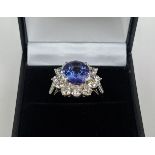 AN 18CT WHITE GOLD TANZANITE AND DIAMOND CLUSTER RING, the central mixed cut stone of 4.95 carats,