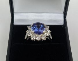 AN 18CT WHITE GOLD TANZANITE AND DIAMOND CLUSTER RING, the central mixed cut stone of 4.95 carats,