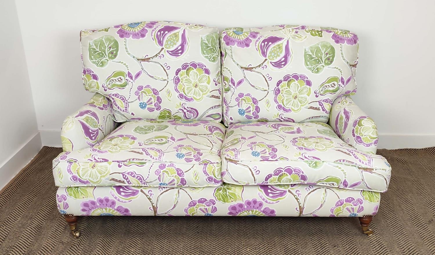 SOFA, purple and green floral patterned on brass castors, 90cm H x 160cm W.