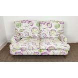 SOFA, purple and green floral patterned on brass castors, 90cm H x 160cm W.