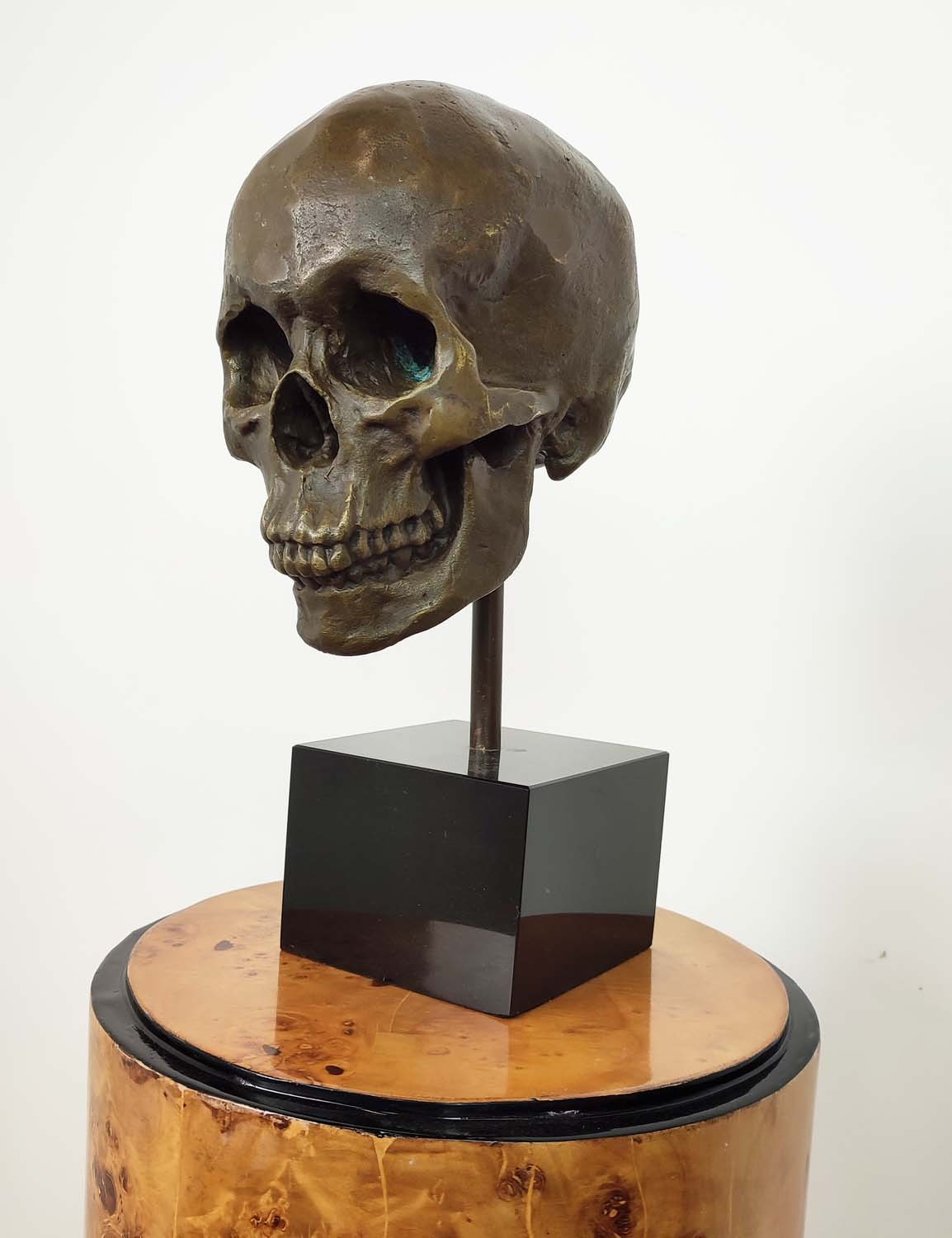 CONTEMPORARY SCHOOL SCULPTURE, bronze, of a skull on a black base, 36cm H.