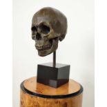 CONTEMPORARY SCHOOL SCULPTURE, bronze, of a skull on a black base, 36cm H.