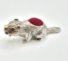 A novelty silver pin cushion in the form of a beaver, with red velvet back, 5 cm long.