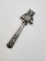 A novelty silver babies rattle, in the form of an owl, with two silver bells, and repousse decorated