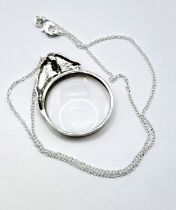 A novelty silver mounted magnifying glass pendant, the round glass surmounted with a horse's head,