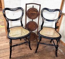 A pair of ebonised bedroom chairs, with mother-of-pearl inlay and some faded gilt decoration, rattan