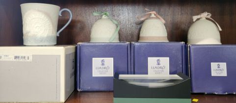 Three Lladro bells, mug and a rectangular display stand in boxes.