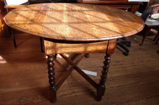 An early 20th century oak drop leaf table (extends to oval-shape), supported on barley twist legs