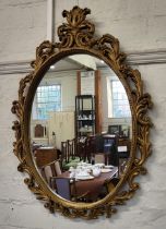 An oval mirror, in ornate giltwood frame. 92cm x 66cm.