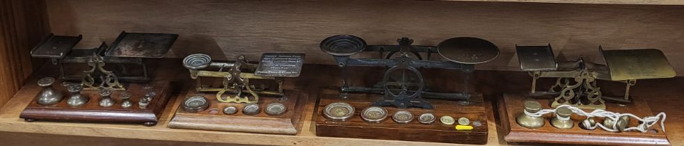A set of four vintage weighing scales, with brass weights, on wooden base.