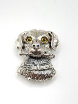 A novelty silver brooch / pendant in the form of a dog carrying a lead in his mouth, with yellow