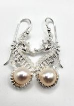 A pair of silver earrings in the form of seahorses, each set with a pearl, approximately 3 cm