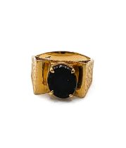 A yellow metal and black onyx ring, with raised pyramid detail to shoulders, centred with an oval