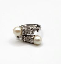 A diamond and pearl crossover cocktail ring, the stylised terminals inset with diamonds, and each