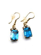 A pair of yellow metal, diamond, and blue topaz earrings, each set with a rectangular-cut topaz