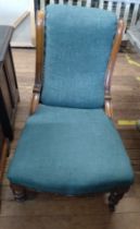 A nursing chair with green upholstery on turned front legs and casters.