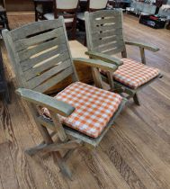 A pair of foldable wooden garden chairs, with chequered cushions.