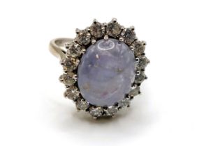 An 18ct white gold, diamond, and star sapphire ring, set with a pale blue cabochon sapphire, showing