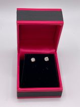 A pair of 14ct white gold mounted solitaire diamond earrings, the round brilliant-cut diamonds of