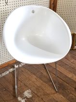 A vintage style white tub chair, supported on shaped stainless steel lets.