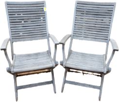 A pair of slatted wood folding garden armchairs, 95cm high, 55cm wide and 65cm deep. (2)