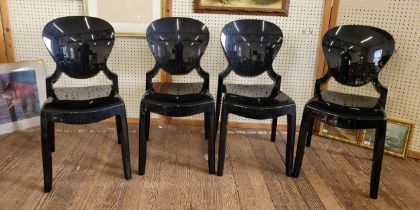 A set of four black plastic moulded chairs, with rounded backs and plain seats, tapered legs.