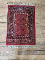 A red ground prayer rug, double bordered and fringed. 103cm x 65cm